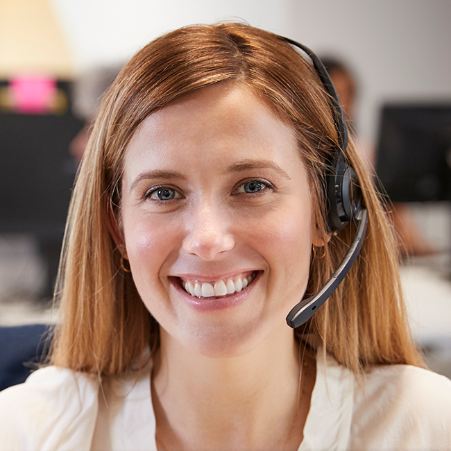 Young woman working at computer with headset in busy office